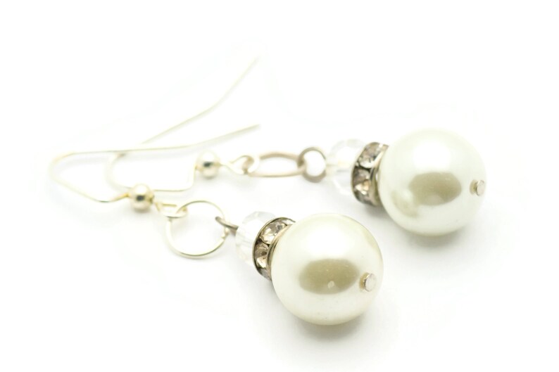 Peut inclure: Une paire de boucles d'oreilles en argent avec des accents de perles blanches et de cristal.