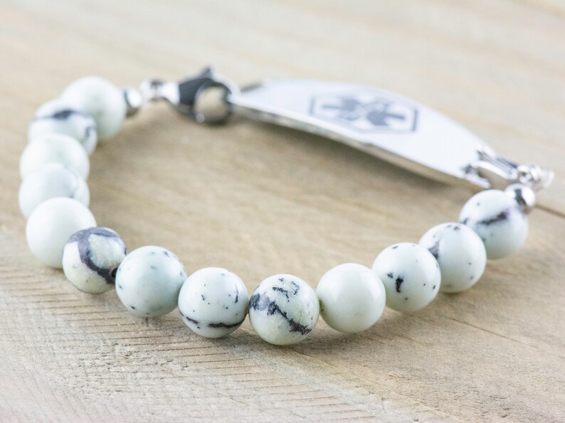 Peut inclure: Un bracelet en perles de pierre blanches et noires avec une plaque d'identification m&eacute;dicale en argent. La plaque comporte un symbole m&eacute;dical et un espace pour la gravure.