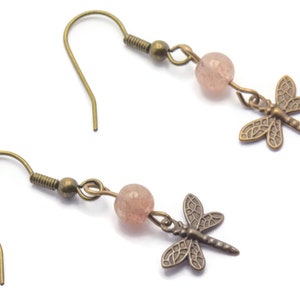 May include: A pair of bronze dragonfly earrings with pink glass beads. The earrings have a hook fastening.