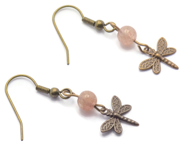 May include: A pair of bronze dragonfly earrings with pink glass beads. The earrings have a hook fastening.