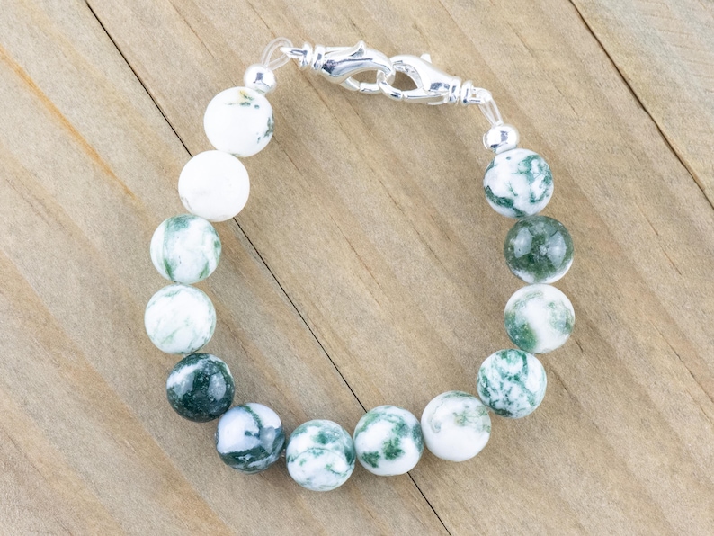 May include: A green and white agate stone bracelet with a silver clasp. The bracelet is made of round beads and is approximately 18 cm in length.