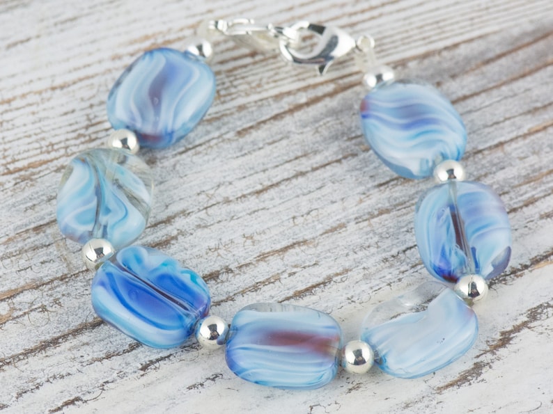 May include: A bracelet made of blue and white swirled glass beads with silver spacers and a silver clasp.