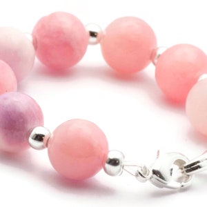 Puede incluir: Una pulsera con cuentas redondas rosas en diferentes tonos, desde rosa claro hasta un rosa m&aacute;s intenso. Las cuentas est&aacute;n unidas con peque&ntilde;as cuentas de metal plateado y un cierre plateado. La pulsera est&aacute; dise&ntilde;ada para ser usada alrededor de la mu&ntilde;eca.
