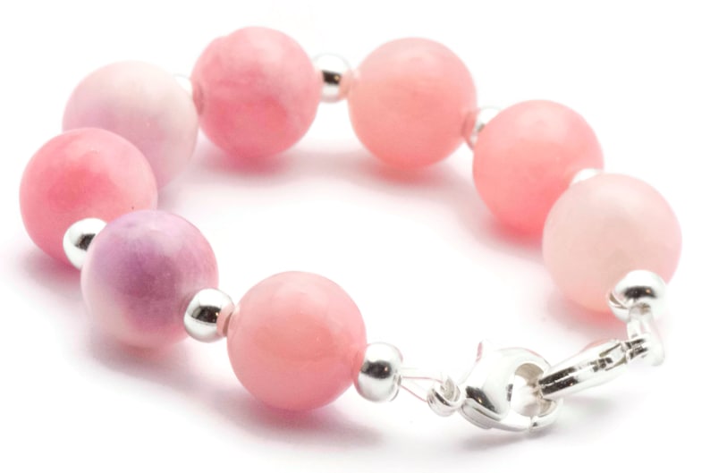 Puede incluir: Una pulsera con cuentas redondas rosas en diferentes tonos, desde rosa claro hasta un rosa m&aacute;s intenso. Las cuentas est&aacute;n unidas con peque&ntilde;as cuentas de metal plateado y un cierre plateado. La pulsera est&aacute; dise&ntilde;ada para ser usada alrededor de la mu&ntilde;eca.
