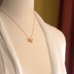 Peut inclure: Un collier en cha&icirc;ne dor&eacute;e avec un pendentif d&eacute;licat en forme de papillon.