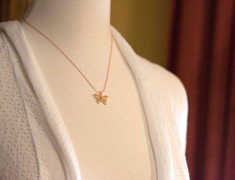 Peut inclure: Un collier en cha&icirc;ne dor&eacute;e avec un pendentif d&eacute;licat en forme de papillon.