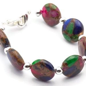 May include: A bracelet made of oval-shaped, multi-colored stones with silver accents. The stones are a mix of green, blue, pink, and brown.