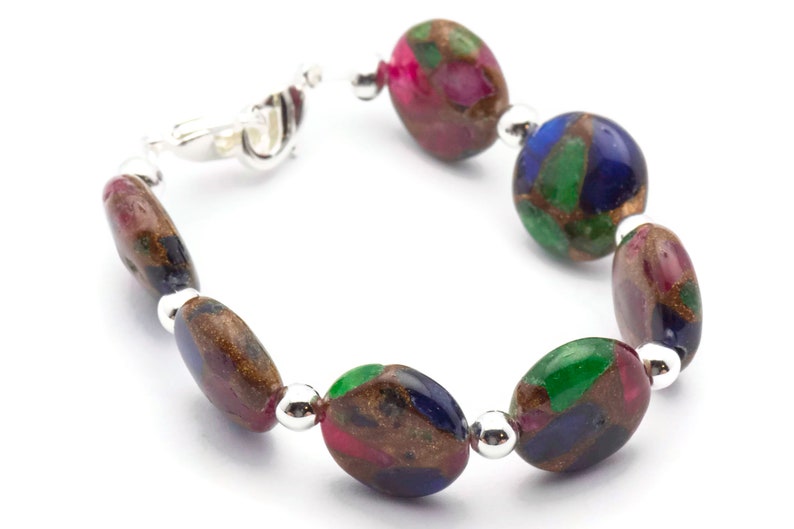 May include: A bracelet made of oval-shaped, multi-colored stones with silver accents. The stones are a mix of green, blue, pink, and brown.