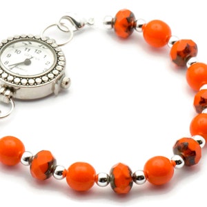 May include: A silver watch with a white face and black hands attached to a bracelet of orange and silver beads.