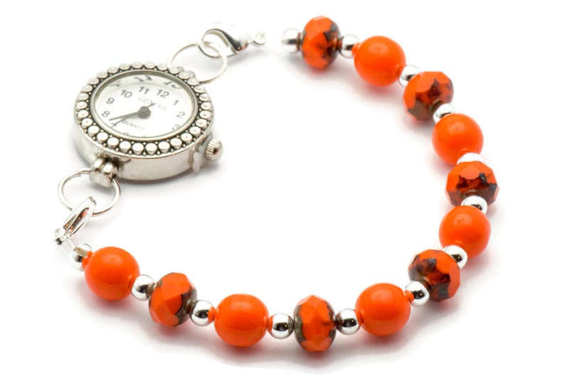 May include: A silver watch with a white face and black hands attached to a bracelet of orange and silver beads.