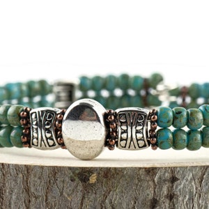 Button and Bows Desert Turquoise Cuff Memory Wire Bracelet close up on a wood piece with tree bark edging