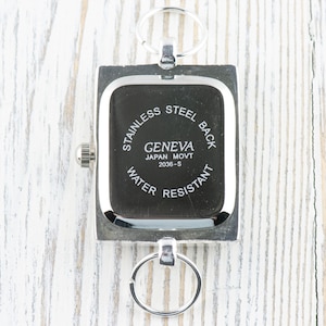 May include: Silver square watch with a black face and the text "Stainless Steel Back Geneva Japan Movt 2036-S Water Resistant" printed on the back.