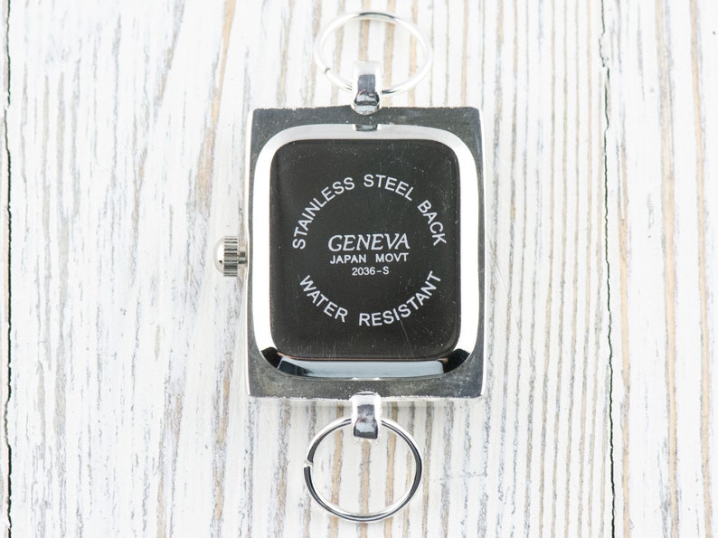 May include: Silver square watch with a black face and the text "Stainless Steel Back Geneva Japan Movt 2036-S Water Resistant" printed on the back.
