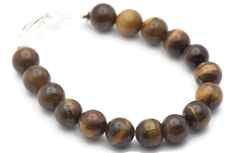 Op de afbeelding: Een bruine en gouden tijgeroog kralen armband met een zilveren sluiting.