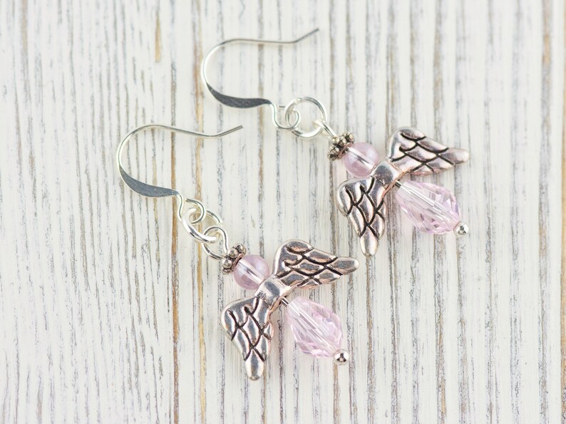 May include: A pair of silver angel wing earrings with pink crystal beads.