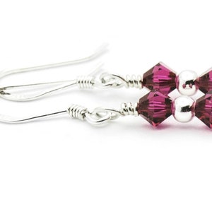 Puede incluir: Un par de pendientes de plata con dos peque&ntilde;as cuentas de cristal rosa oscuro en cada pendiente.