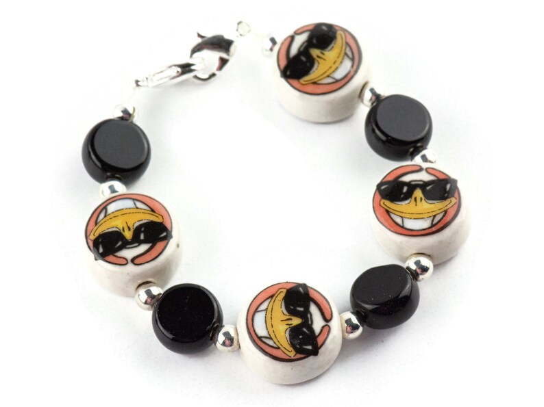 May include: A bracelet with black and white ceramic beads. The white beads feature a cartoon duck wearing sunglasses.
