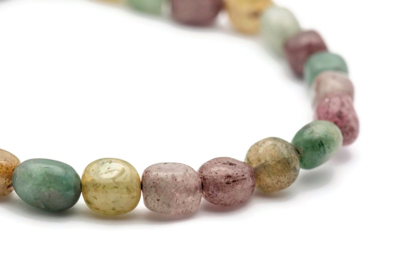 May include: A bracelet made of smooth, oval-shaped beads in shades of green, pink, and brown.