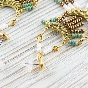 May include: A pair of gold tone earrings with turquoise and white beads, and a gold tone hook closure.