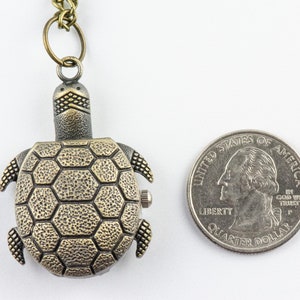 May include: A bronze turtle-shaped pocket watch with a chain. The watch is about the size of a quarter.