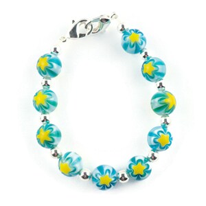 Peut inclure: Un bracelet en perles turquoise et blanches avec des accents d'&eacute;toiles jaunes et un fermoir argent&eacute;.