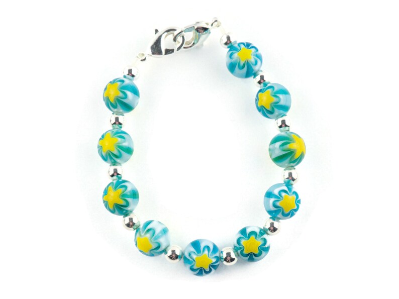 Peut inclure: Un bracelet en perles turquoise et blanches avec des accents d'&eacute;toiles jaunes et un fermoir argent&eacute;.