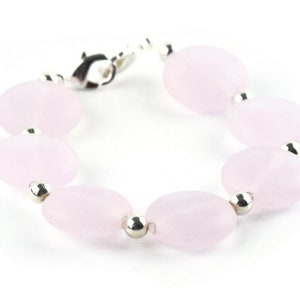May include: A bracelet made of pale pink oval-shaped beads with silver accents.