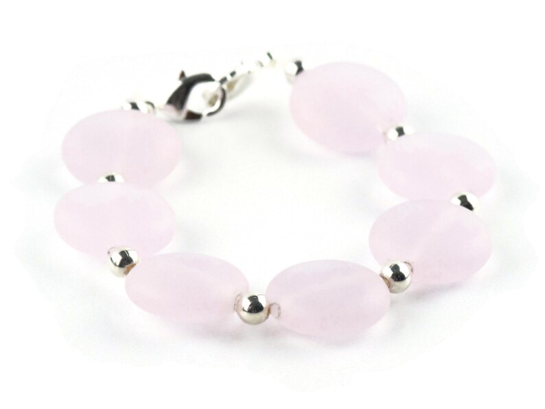 May include: A bracelet made of pale pink oval-shaped beads with silver accents.