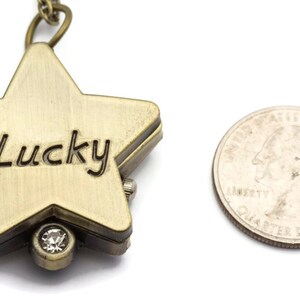 Peut inclure: Une montre de poche en forme d'&eacute;toile dor&eacute;e avec une cha&icirc;ne et un strass transparent. Le cadran de la montre est grav&eacute; du mot "Lucky".