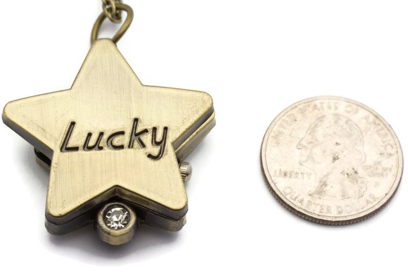 Peut inclure: Une montre de poche en forme d'&eacute;toile dor&eacute;e avec une cha&icirc;ne et un strass transparent. Le cadran de la montre est grav&eacute; du mot "Lucky".