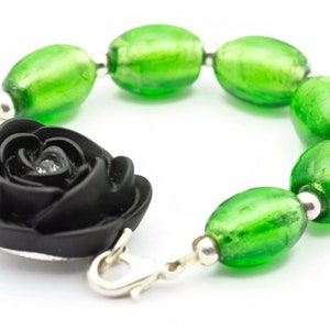 May include: A black rose charm bracelet with green glass beads. The bracelet has a silver clasp.