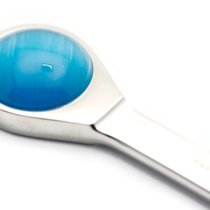 K&ouml;nnte beinhalten: Nahaufnahme eines silberfarbenen Werkzeugs mit einem blauen, runden, glasartigen Kopf.