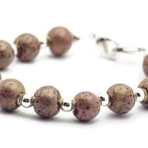 May include: A bracelet made of brown and pink speckled beads with silver accents.