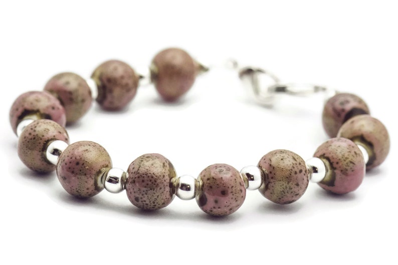 May include: A bracelet made of brown and pink speckled beads with silver accents.