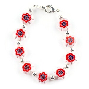 Puede incluir: Un brazalete de plata con cuentas de vidrio blancas y rojas con un dise&ntilde;o floral. Las cuentas tienen un centro multicolor con acentos rojos, azules y blancos.