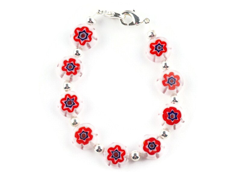 Puede incluir: Un brazalete de plata con cuentas de vidrio blancas y rojas con un dise&ntilde;o floral. Las cuentas tienen un centro multicolor con acentos rojos, azules y blancos.