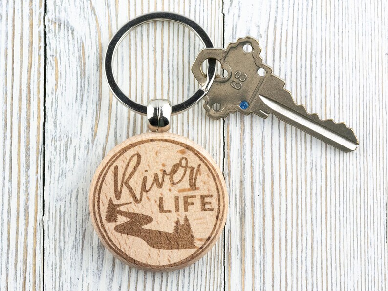 May include: A wooden keyring with a silver key ring. The keyring is round and has the words "River Life" engraved on it. There is a small image of a river and trees engraved on the keyring.