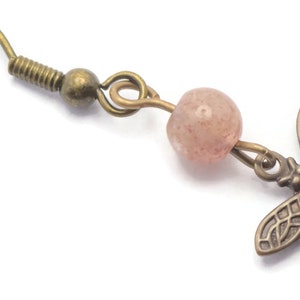 May include: A pair of bronze earrings with a pink gemstone bead and a dragonfly charm.