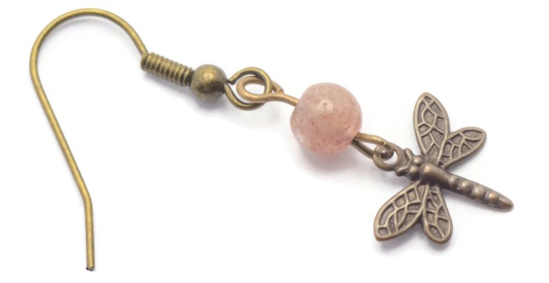 May include: A pair of bronze earrings with a pink gemstone bead and a dragonfly charm.