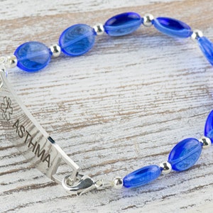 May include: A blue beaded bracelet with a silver medical alert tag that reads "ASTHMA".