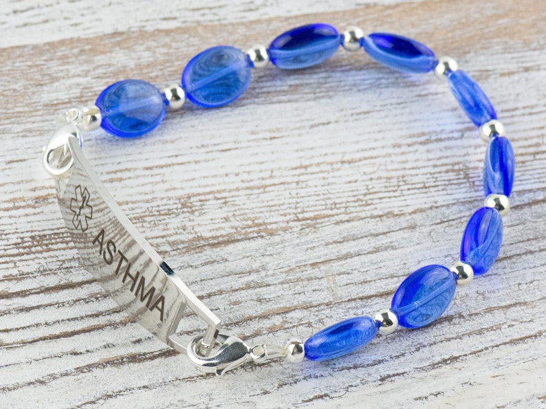 May include: A blue beaded bracelet with a silver medical alert tag that reads "ASTHMA".