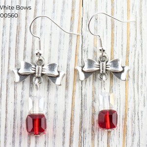 Pode incluir: Brincos de la&ccedil;o prateados com uma gota de joia transparente e vermelha. Os brincos t&ecirc;m fecho de gancho. O texto "Red & White Bows" e "EA00560" est&aacute; no canto superior esquerdo.
