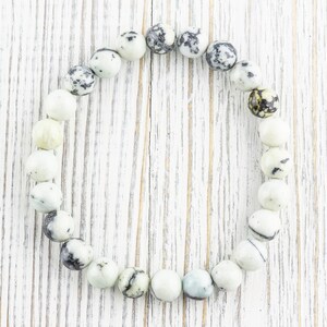 May include: A white and black speckled stone bracelet with round beads.