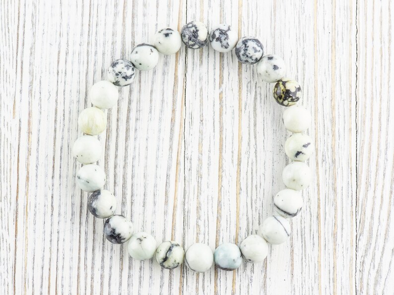 May include: A white and black speckled stone bracelet with round beads.