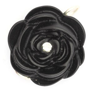 May include: A black rose-shaped charm with a clear rhinestone in the center. The charm has a silver loop for attaching to a necklace or bracelet.