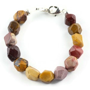 May include: A multi-colored gemstone bracelet with a silver clasp. The bracelet features a variety of colors, including red, brown, and yellow.