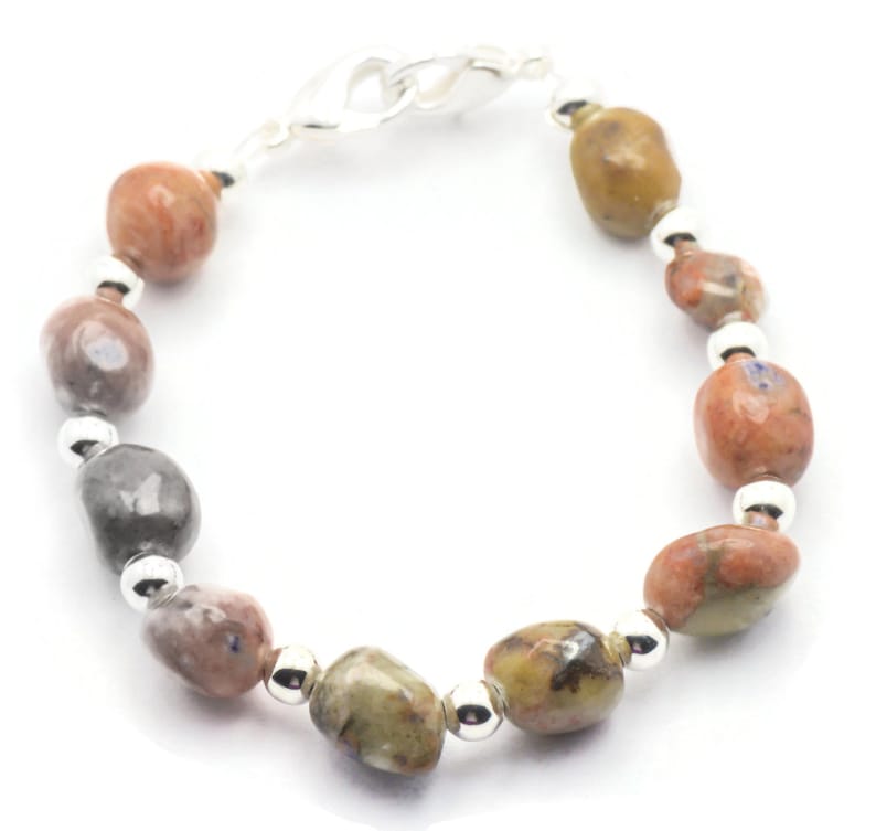 May include: A bracelet made with brown, gray, and white stones. The bracelet has a silver clasp.