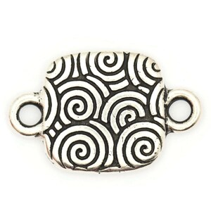 May include: Silver-toned metal connector with a square shape and a swirling pattern. The connector has two loops on either side.