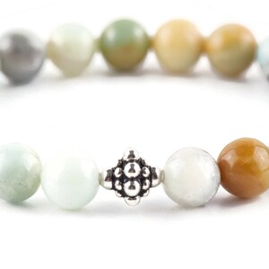 Black Gold Amazonite Genuine Gemstone Stretch Bracelet on white background. Amazonite beads are multicolor earth-tones. Close up of center bead is a silver Bali style bead.