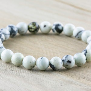 May include: A white and black speckled stone bracelet with round beads.